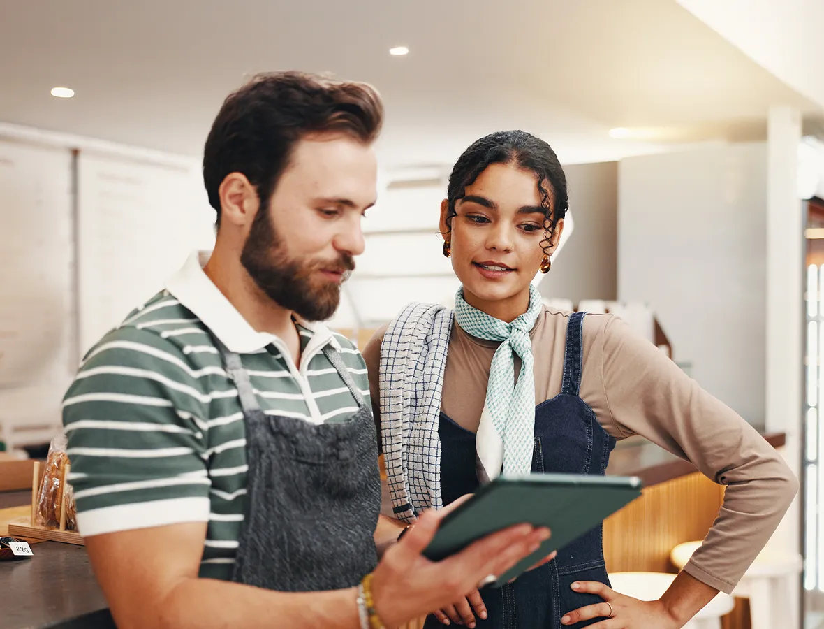 Business owner and employee reviewing SSSCU business lending options on tablet