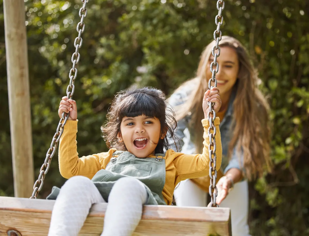 Woman pushing child on a swing