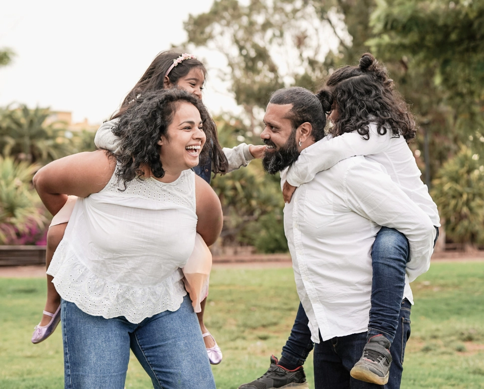 Mother and father giving their daughters piggyback rides